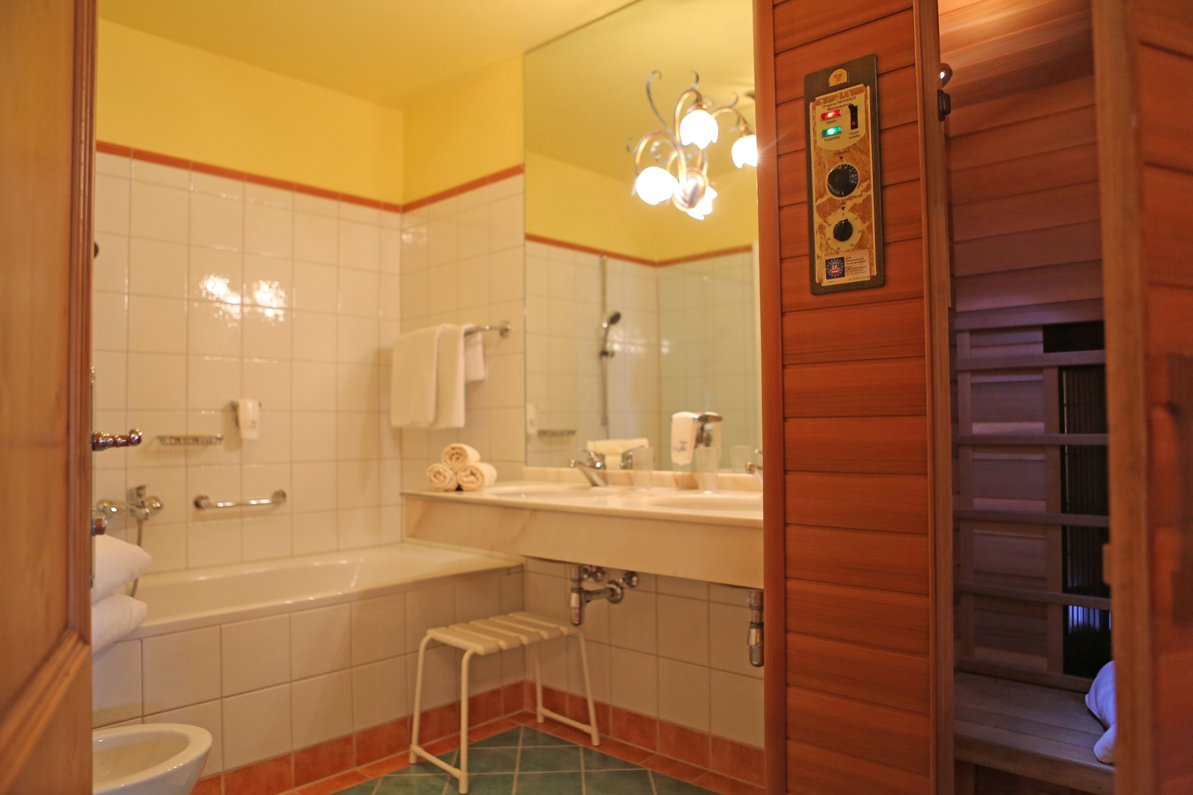 Un baño con bañera, inodoro, lavabo y un taburete pequeño.