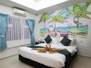 Relax in a serene beach-inspired room with a comfortable bed, a mural of palm trees, and a window with blue curtains.