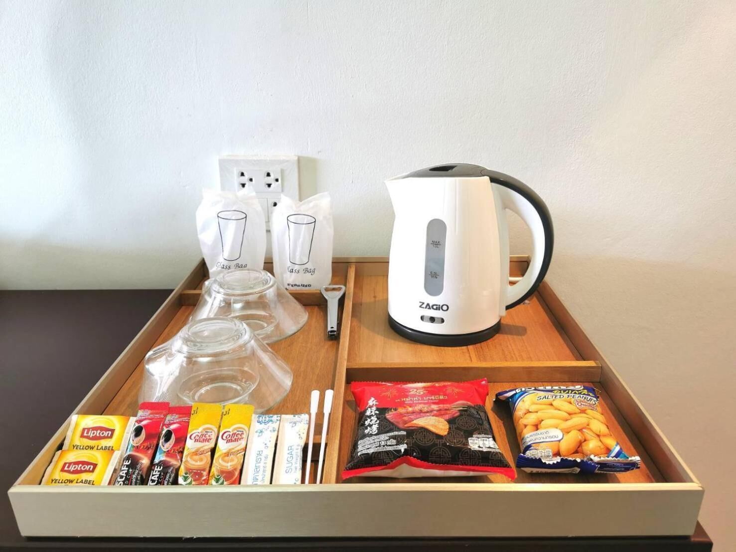 Una bandeja con tetera, frascos de vidrio, paquetes de té Lipton y aperitivos.
