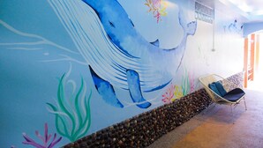 A mural of a whale on a wall, a wicker chair, and a pebble-lined walkway. - Green Bay Samed Resort (Rayong)