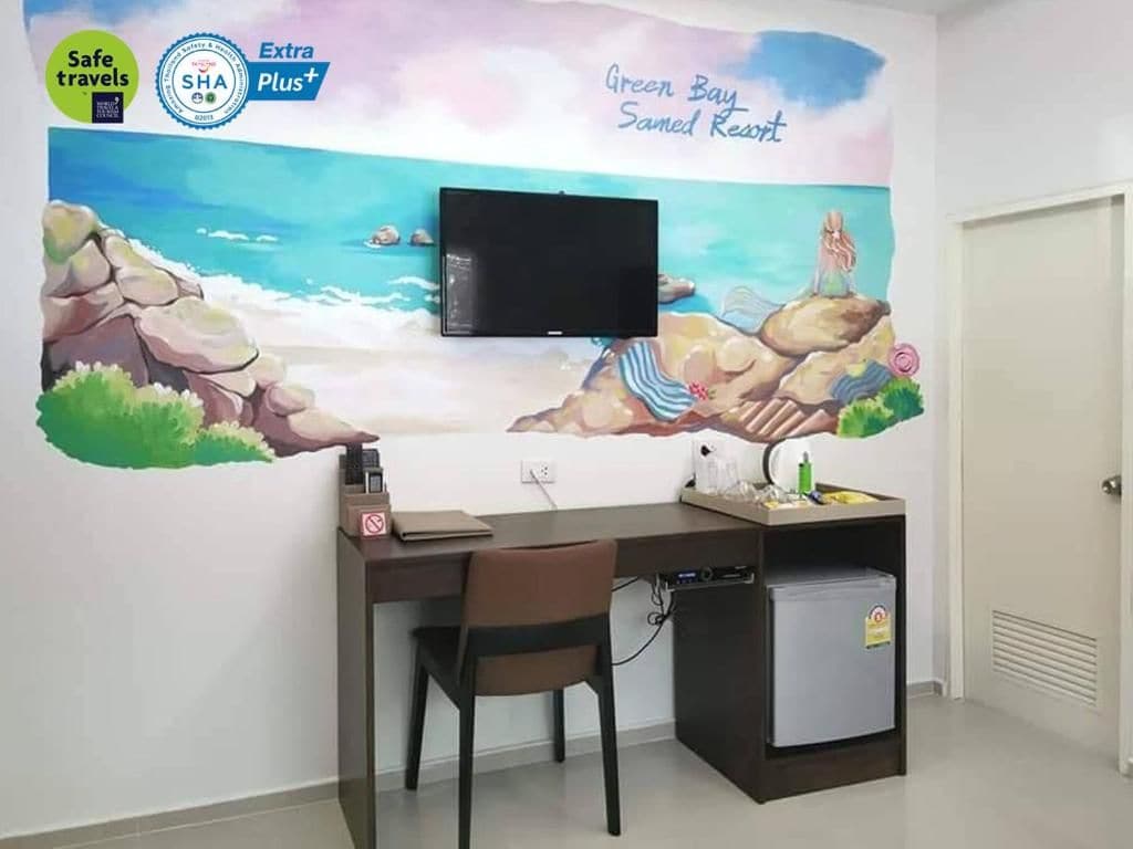 A room with a desk, chair, and a television mounted on the wall.