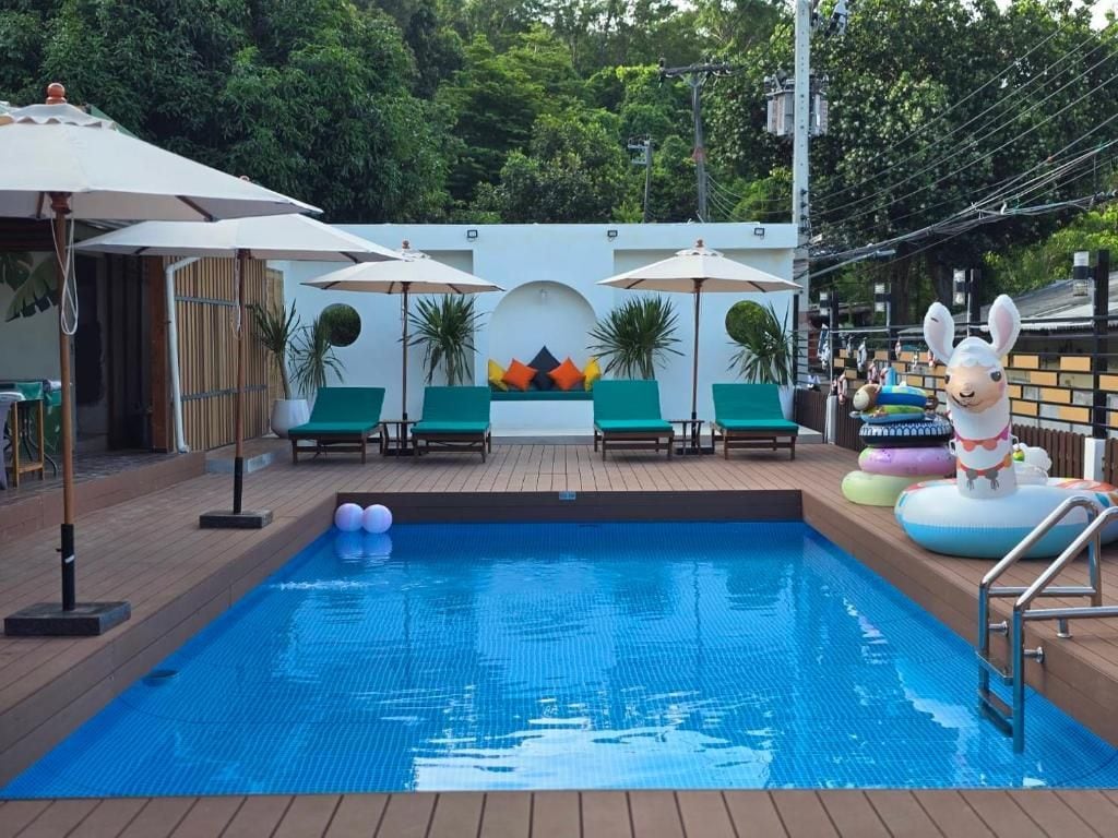 A swimming pool with lounge chairs and umbrellas, surrounded by greenery.