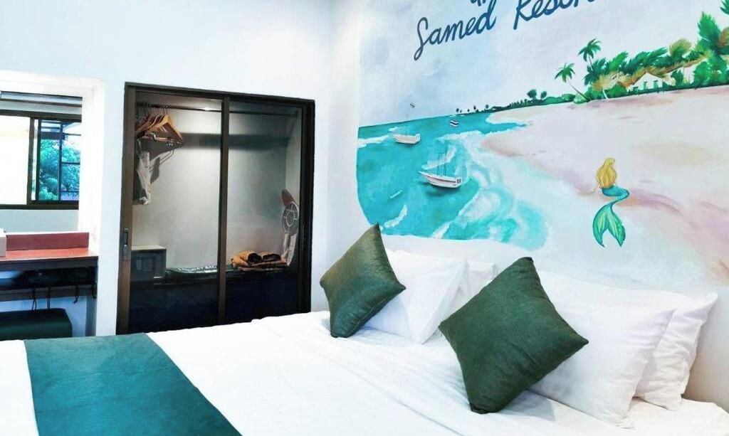 A hotel room with a bed, a desk, and a large mural of a mermaid on the wall.