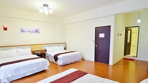 A hotel room with two beds, wooden flooring, a door, and a small nightstand. - Buongiorno B&B-Peng's family (Taitung)