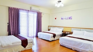 A hotel room with three single beds, a wooden floor, an air conditioning unit, and a window with purple curtains. - Buongiorno B&B-Peng's family (Taitung)
