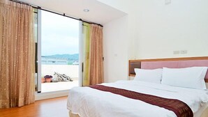 A hotel room with a large bed, a wooden floor, and a view of the outdoors through a sliding door. - Buongiorno B&B-Peng's family (Taitung)