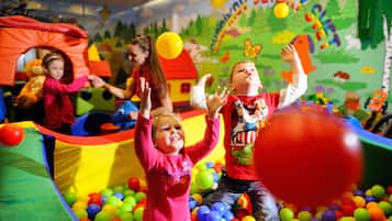 Children playing in a colorful indoor play area with a ball pit and inflatable structures.