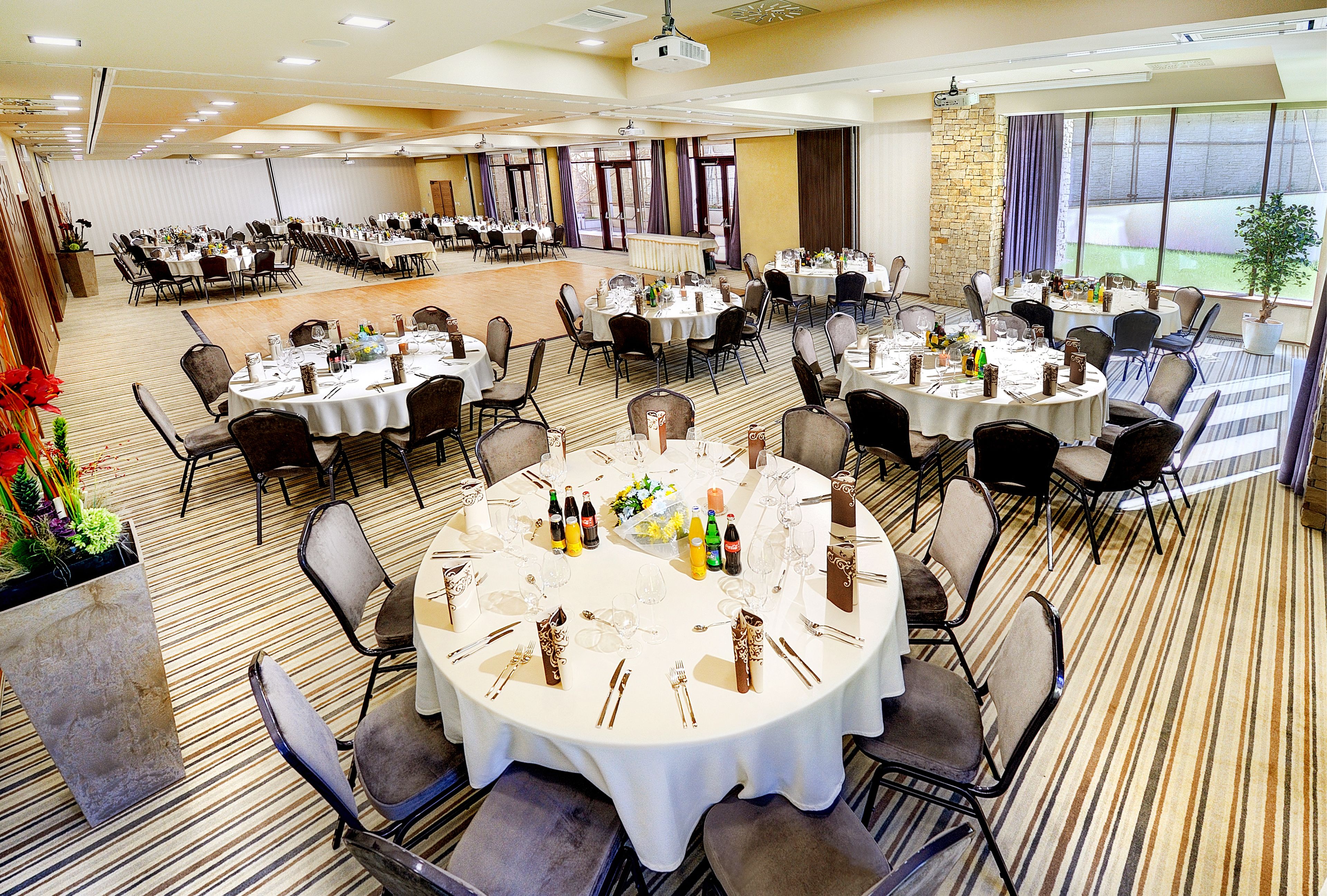 A banquet hall with multiple round tables set for dining, equipped with chairs and table settings.