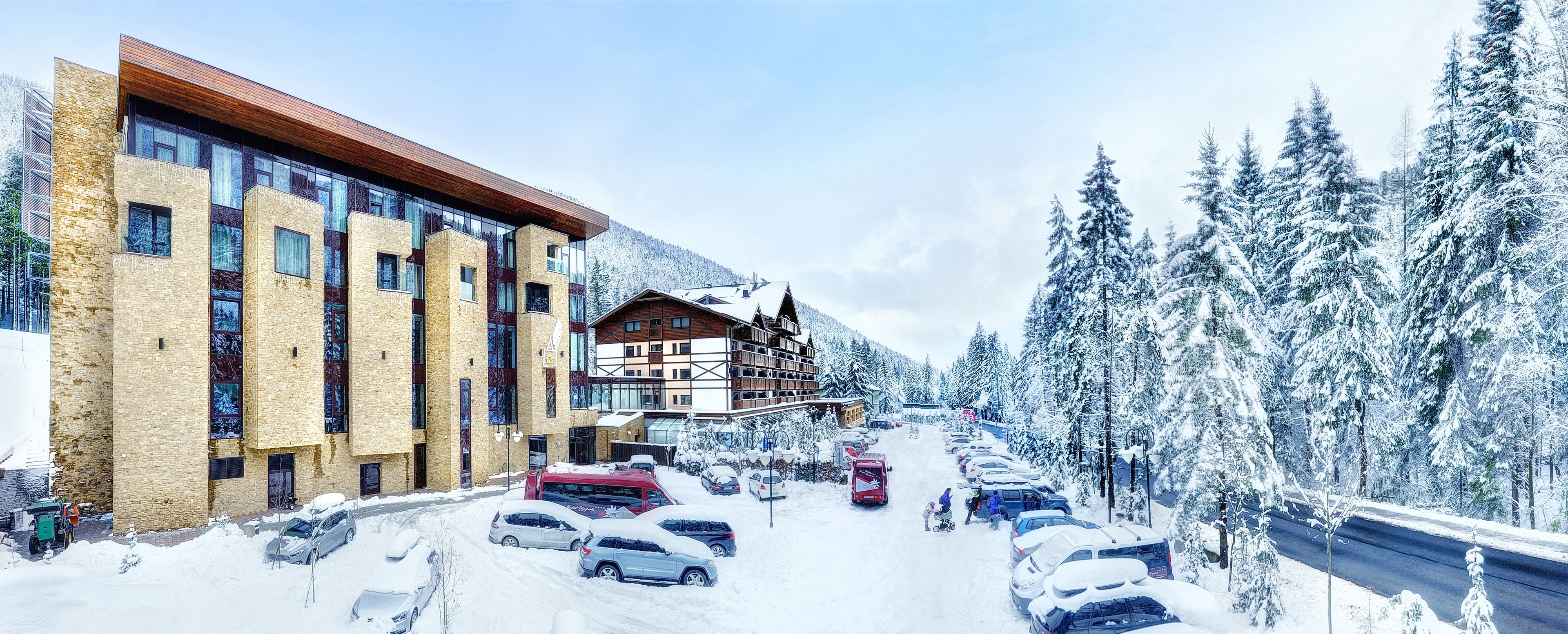 A hotel with a modern design, featuring large windows and a mix of stone and wood materials.