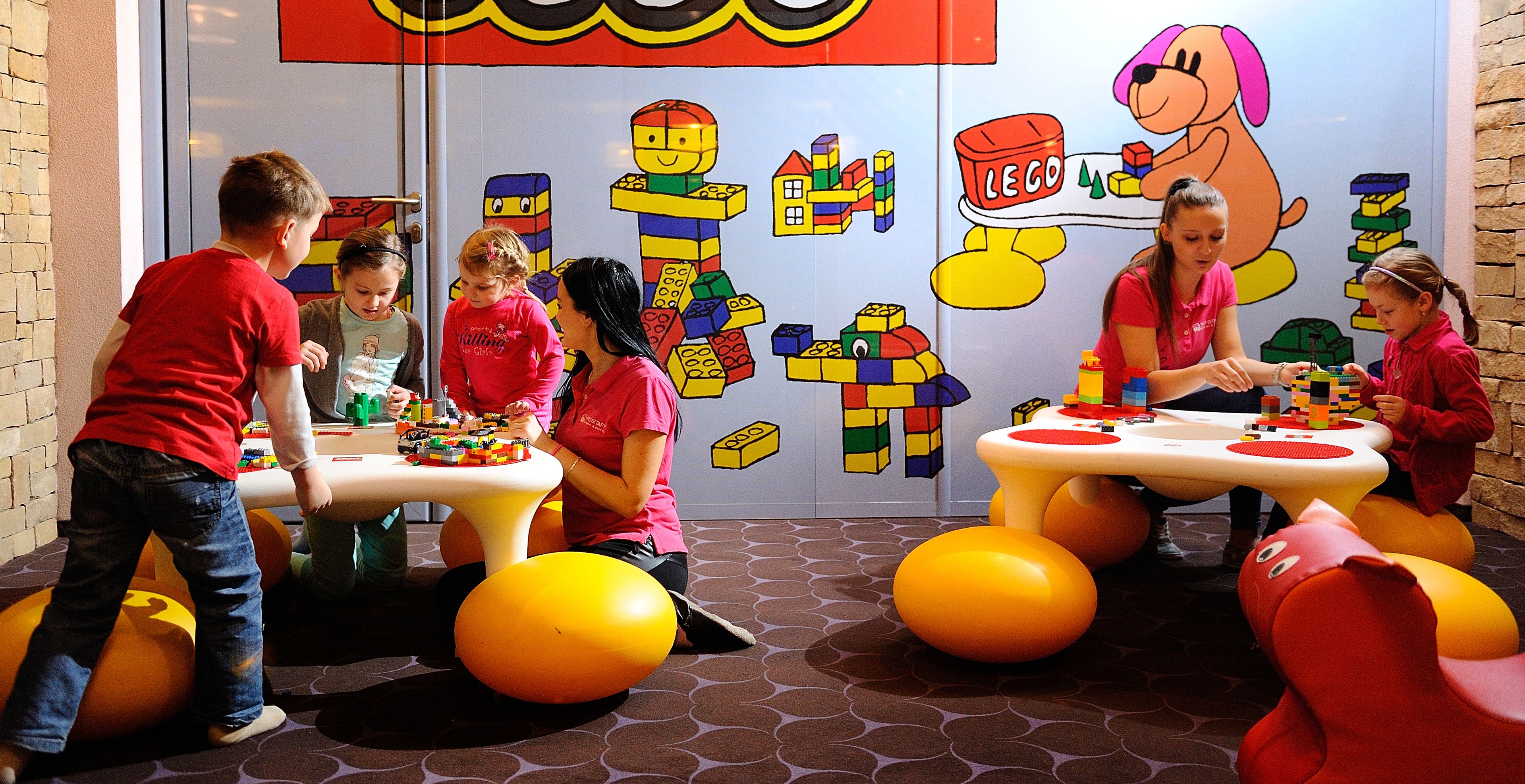A children's play area with tables and colorful balls, featuring LEGO and cartoon character decorations.