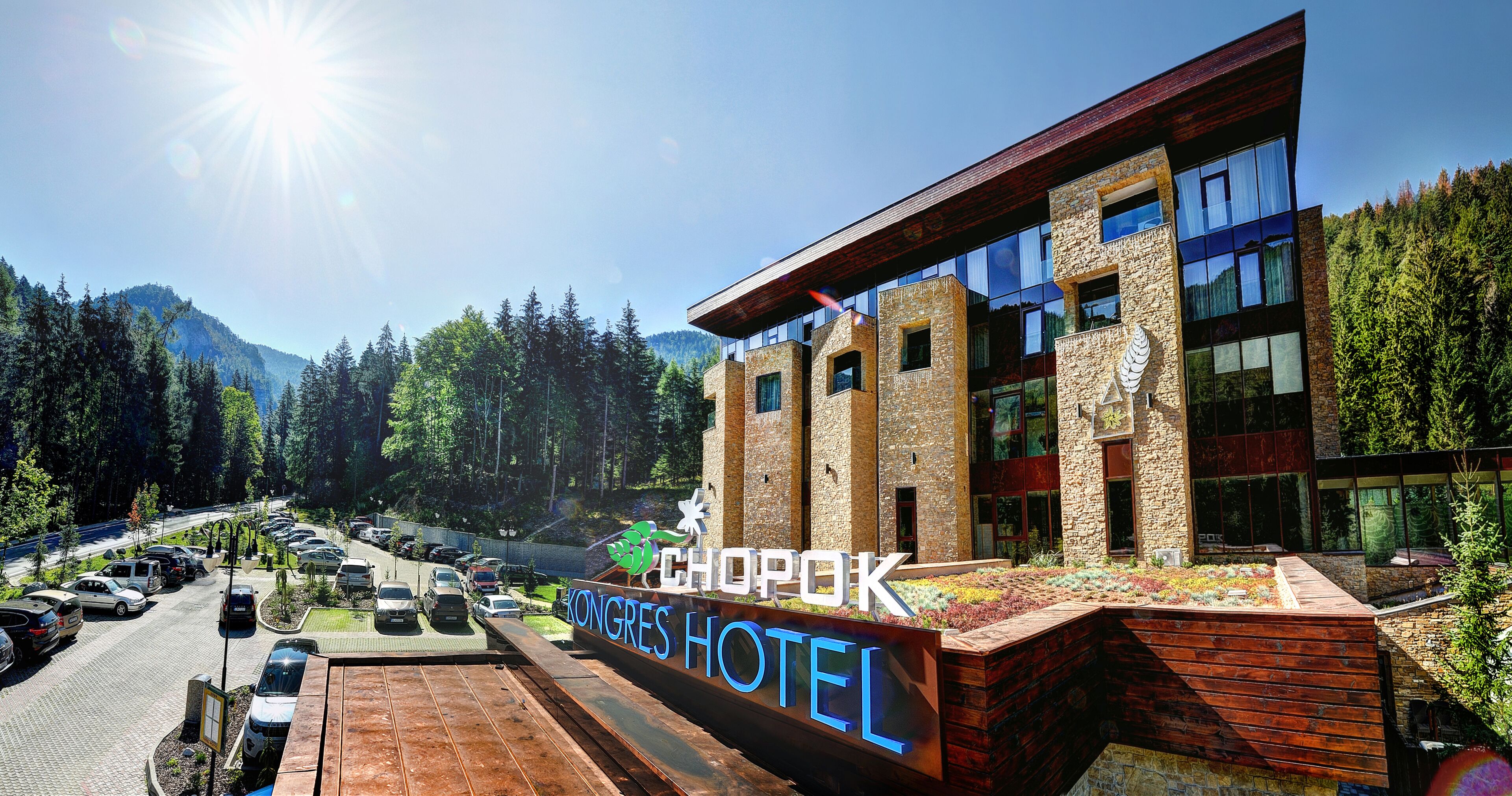 Un hotel con un cartel que dice "Kongres Hotel" y "Chopok" al frente de un paisaje montañoso.
