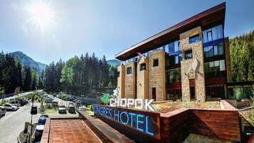 Un hotel con un cartel que dice "Kongres Hotel" y "Chopok" al frente de un paisaje montañoso.