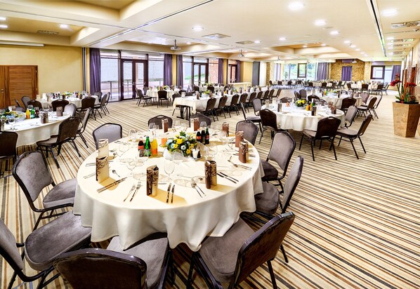 A large conference room with round tables, chairs, and a stage area.