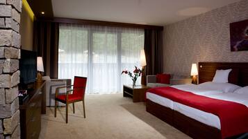 Hotelkamer met een bed, een televisie, een bureau, een stoel en een raam met gordijnen.