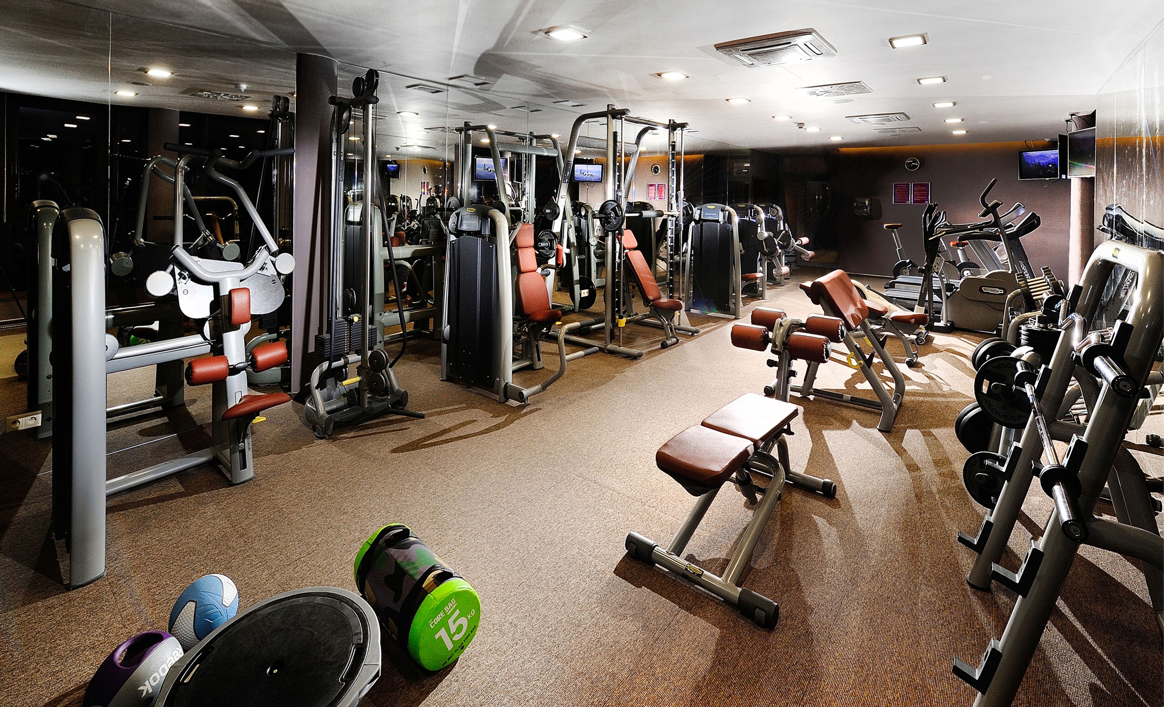 Un gimnasio con diversos equipos de ejercicio, como máquinas de pesas, cintas de correr y pesas libres.
