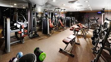 Un gimnasio con diversos equipos de ejercicio, como máquinas de pesas, cintas de correr y pesas libres.