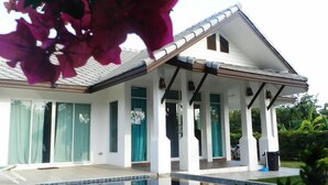 Una casa moderna con piscina, ventanas amplias y un patio cubierto.