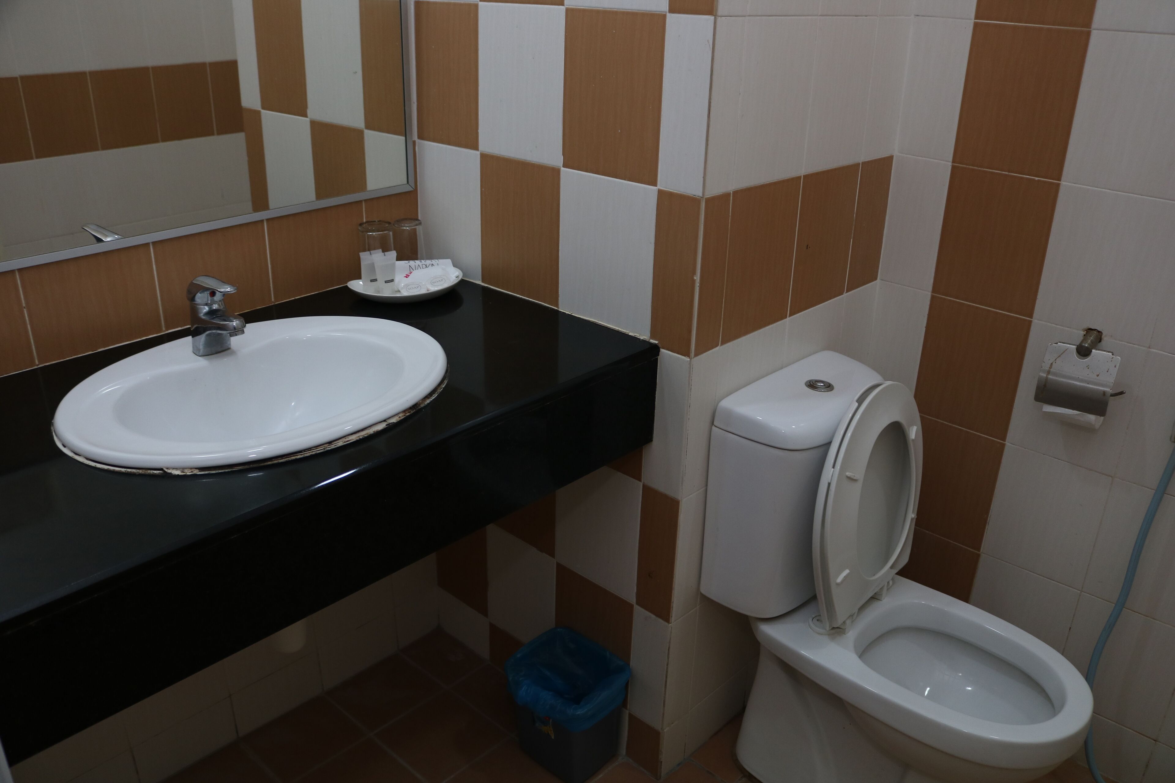 Casa de banho com lavatório branco, bancada preta e sanita.