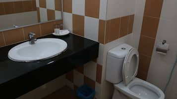 Casa de banho com lavatório branco, bancada preta e sanita.