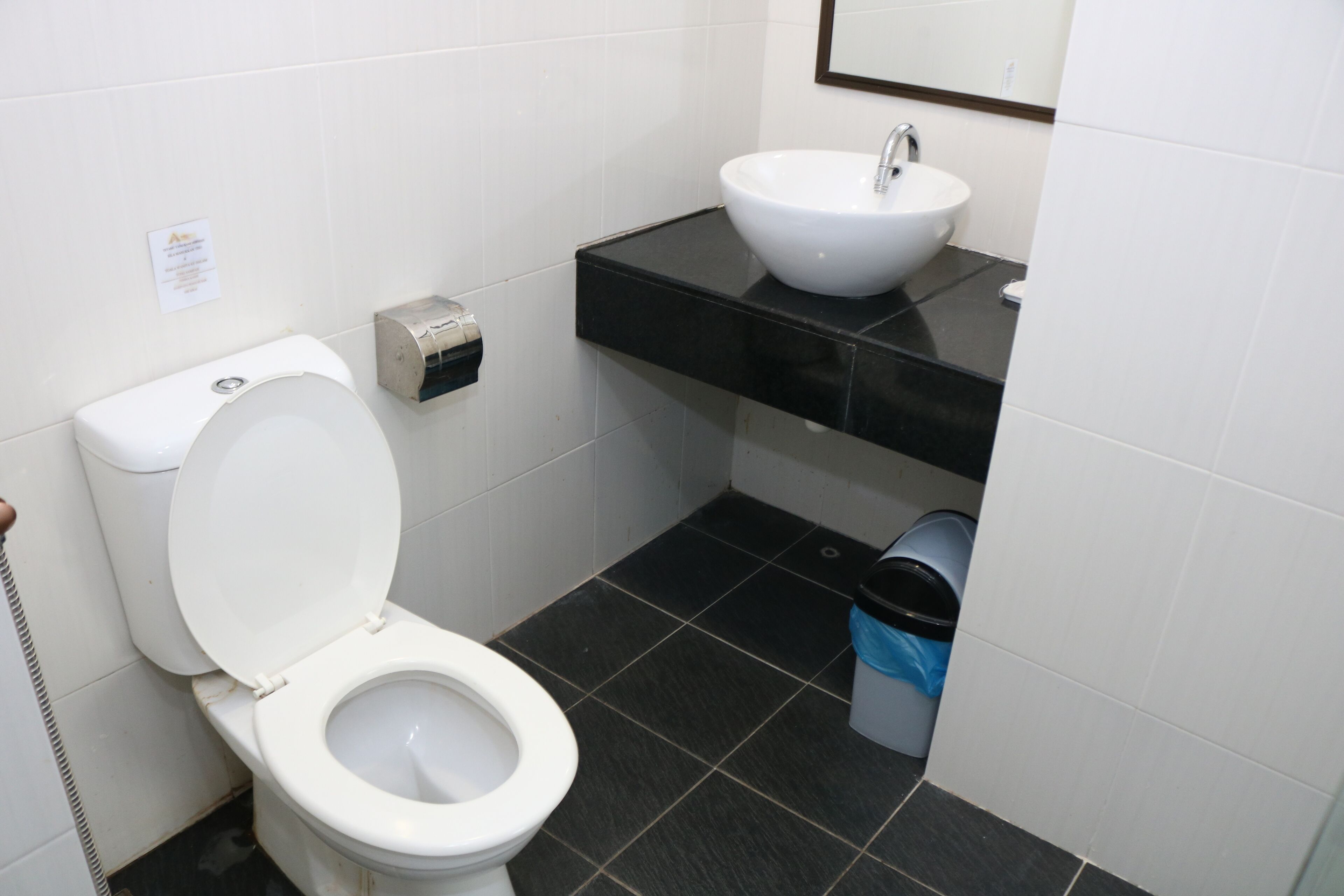 Een badkamer met toilet, wastafel en afvalbak.