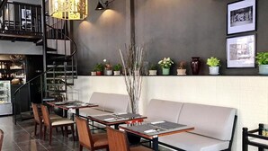Een restaurant interieur met een trap, een zithoek en een muur versierd met ingelijste foto's en potplanten.