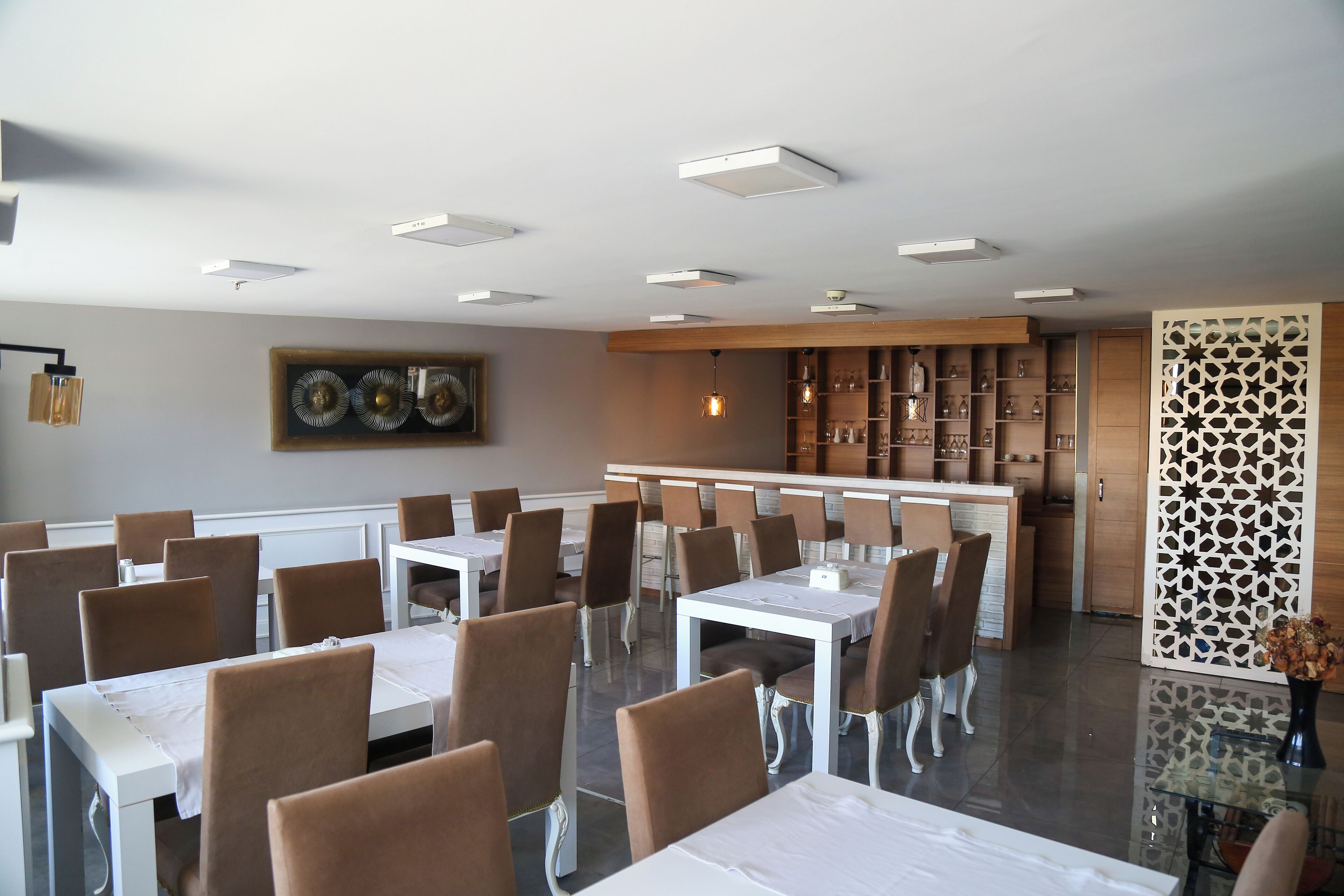 Ein Essbereich mit mehreren Tischen und Stühlen, eine Bar und dekorative Wandverkleidungen.