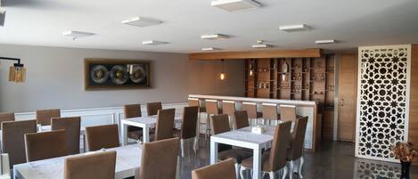 A dining area with multiple tables and chairs, a bar area, and decorative wall panels.