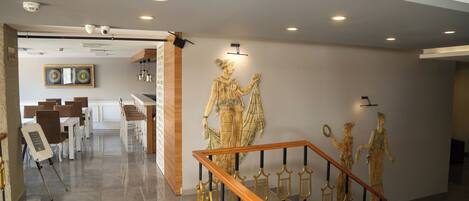 A modern interior with a staircase, a wall-mounted sculpture, and a dining area.
