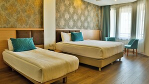 A hotel room with two beds, a wooden headboard, a teal chair, and a large window with curtains. - Start Hotel (Antalya)