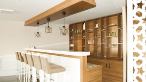 A modern kitchen with a central island, bar stools, wooden cabinets, and pendant lighting. - Start Hotel (Antalya)