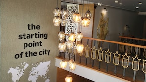 A modern interior with a decorative light fixture and a wall with a map and text. - Start Hotel (Antalya)