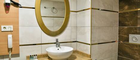 Un baño con un espejo redondo, un lavabo, un perchero para toallas y un inodoro.