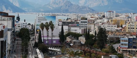 Un paisaje urbano con un cartel llamativo que anuncia VatikBank, Yanindi Gucu y montañas al fondo.