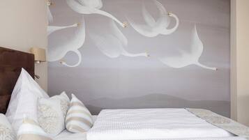 A bedroom with a large wall mural of white swans, a brown headboard, and a bed with white bedding and striped pillows.