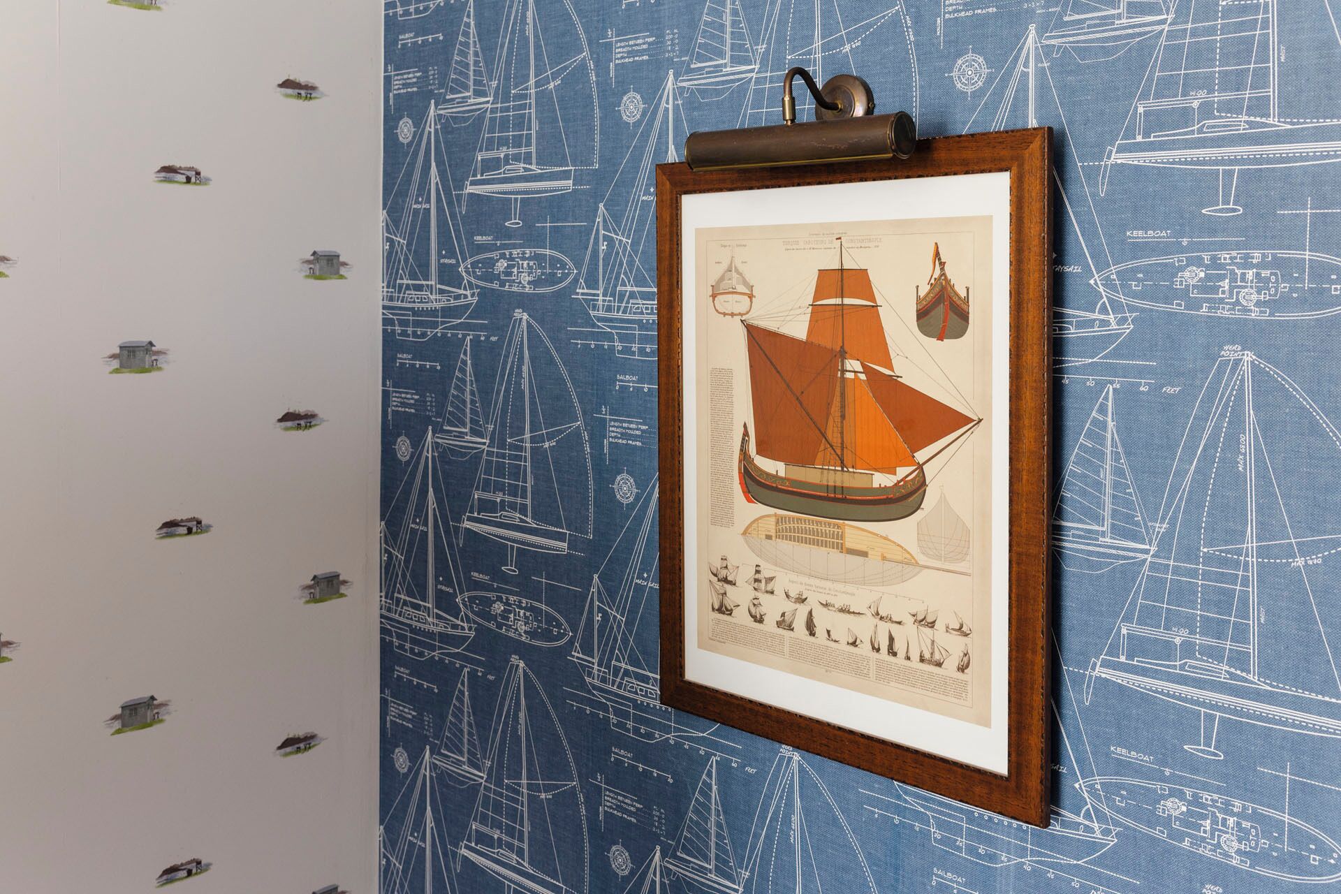A framed illustration of a sailing ship on a blue wall with nautical drawings.