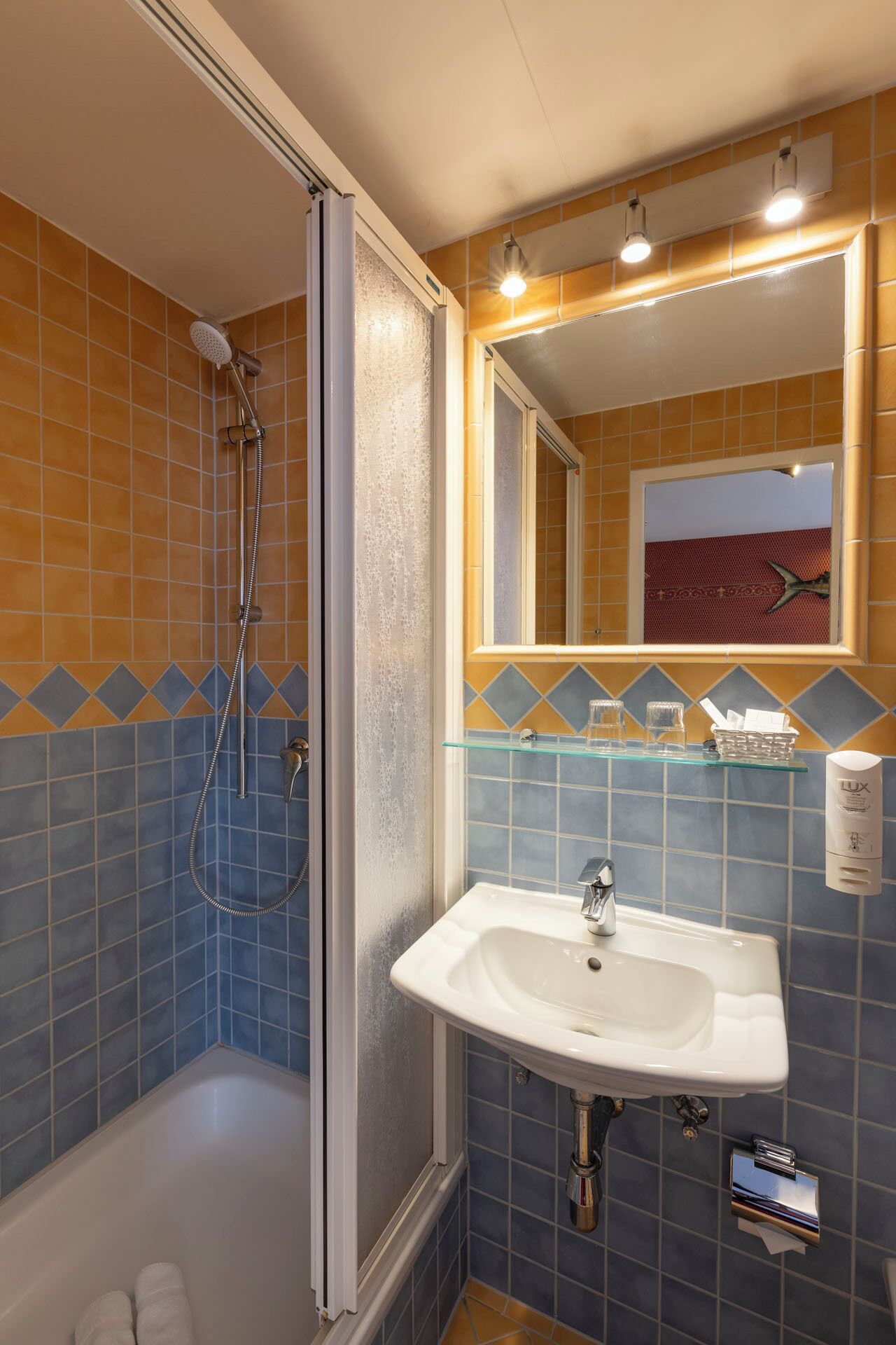 A bathroom with a shower, a sink, and a mirror.