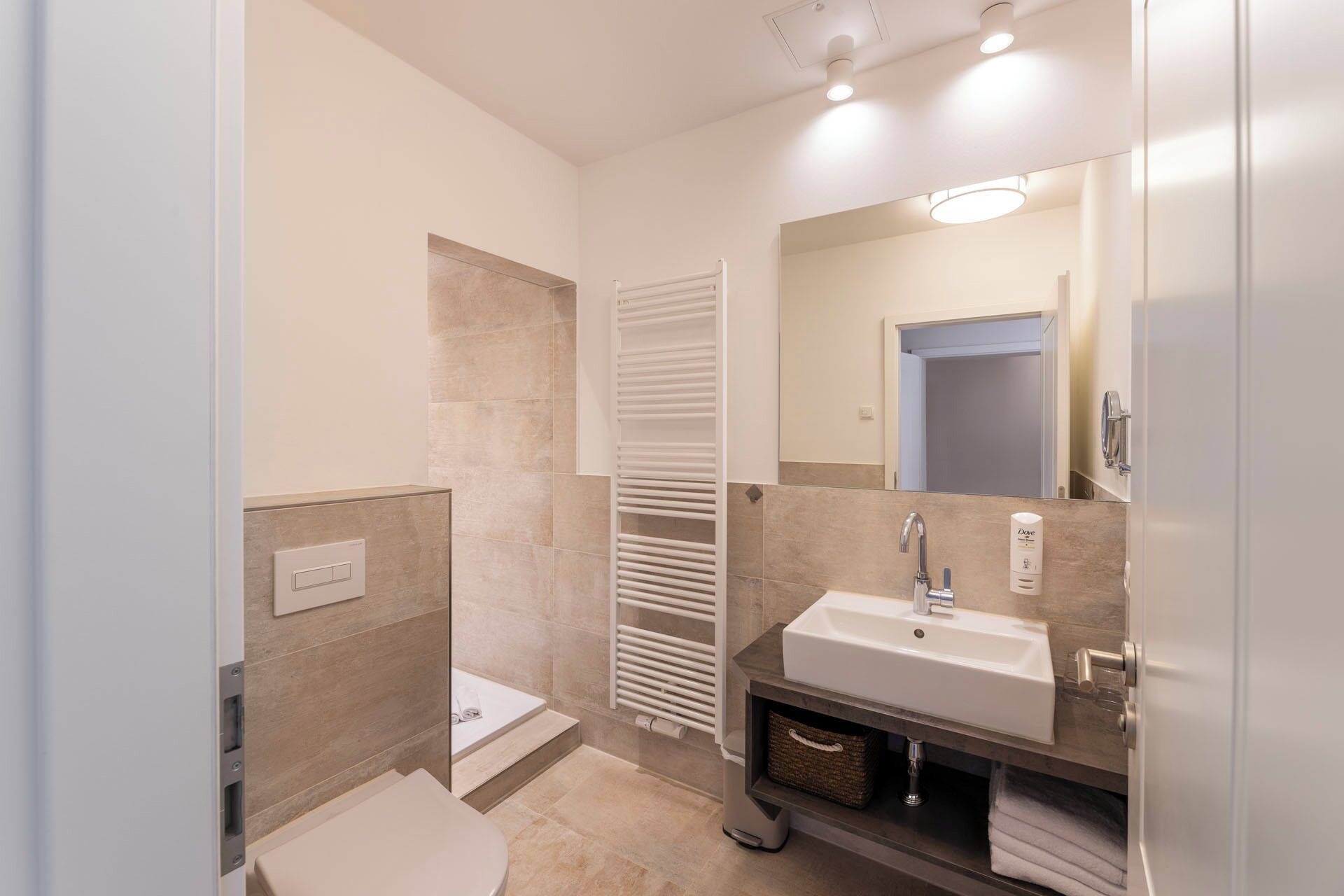Een moderne badkamer met een bad, toilet, wastafel en een grote spiegel.