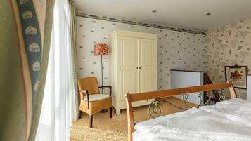 Een slaapkamer met een bed, een stoel, een kledingkast en een bureau.