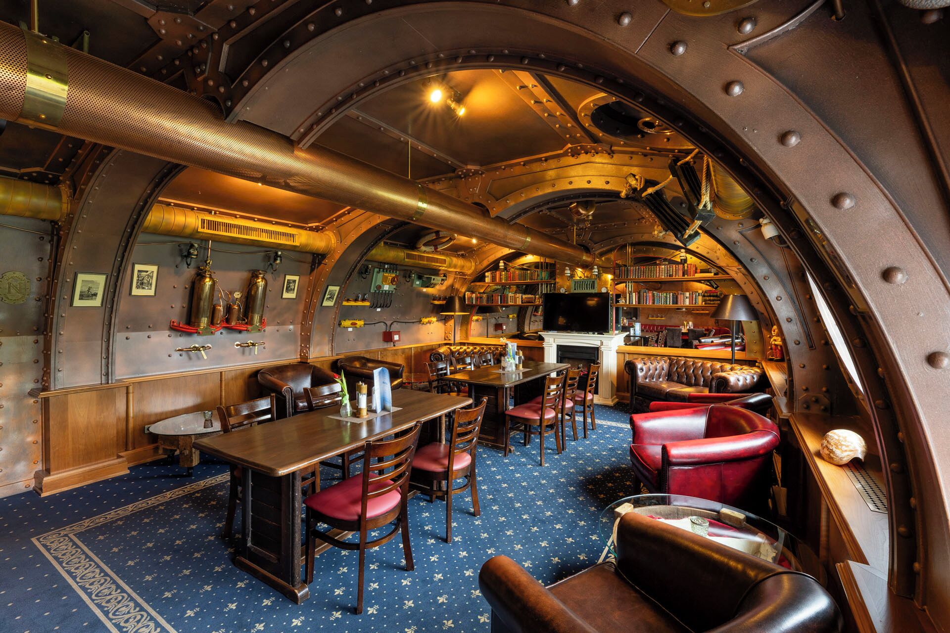 A ship's interior with a bar, seating, bookshelves, and a fireplace.