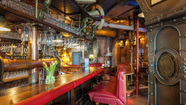 A bar with multiple stools, a bar counter, and a variety of glassware. - Hotel Nautilus (Putbus)
