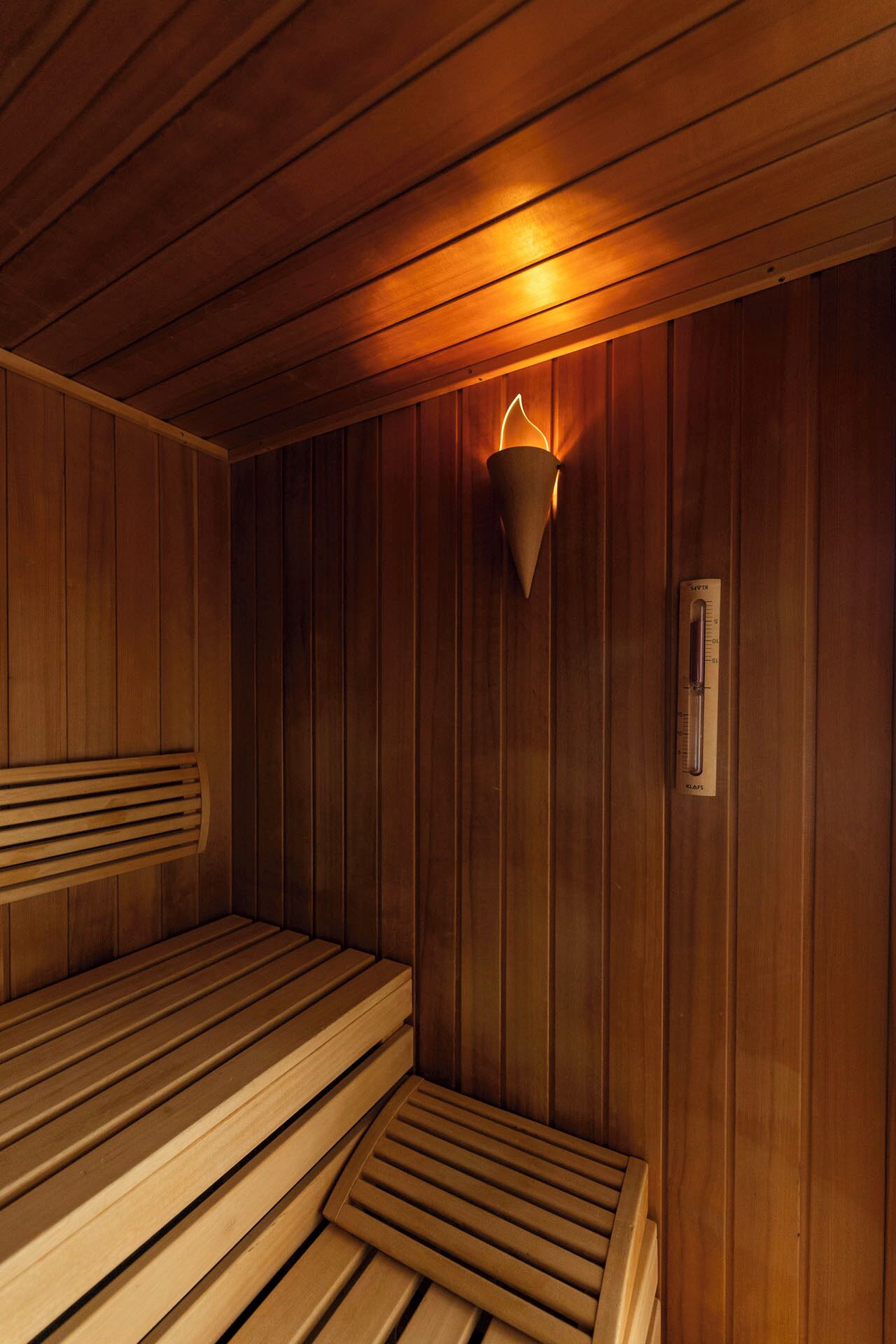 Una sala de sauna con bancos de madera y una lámpara fijada a la pared.