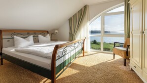 Un dormitorio con cama, una silla y vistas a un lago.