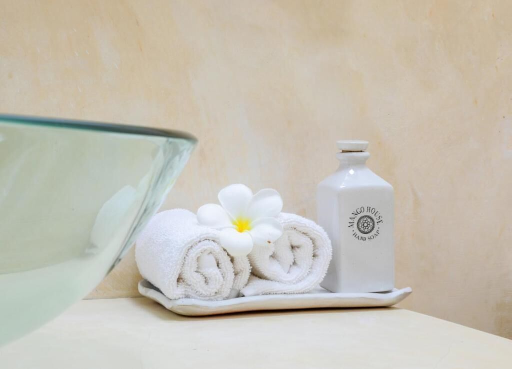 A bathroom with a glass shower, a white towel with a flower, and a bottle of hand soap.