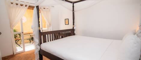 Una cama con dosel, ropa de cama blanca y un cabecero de madera.
