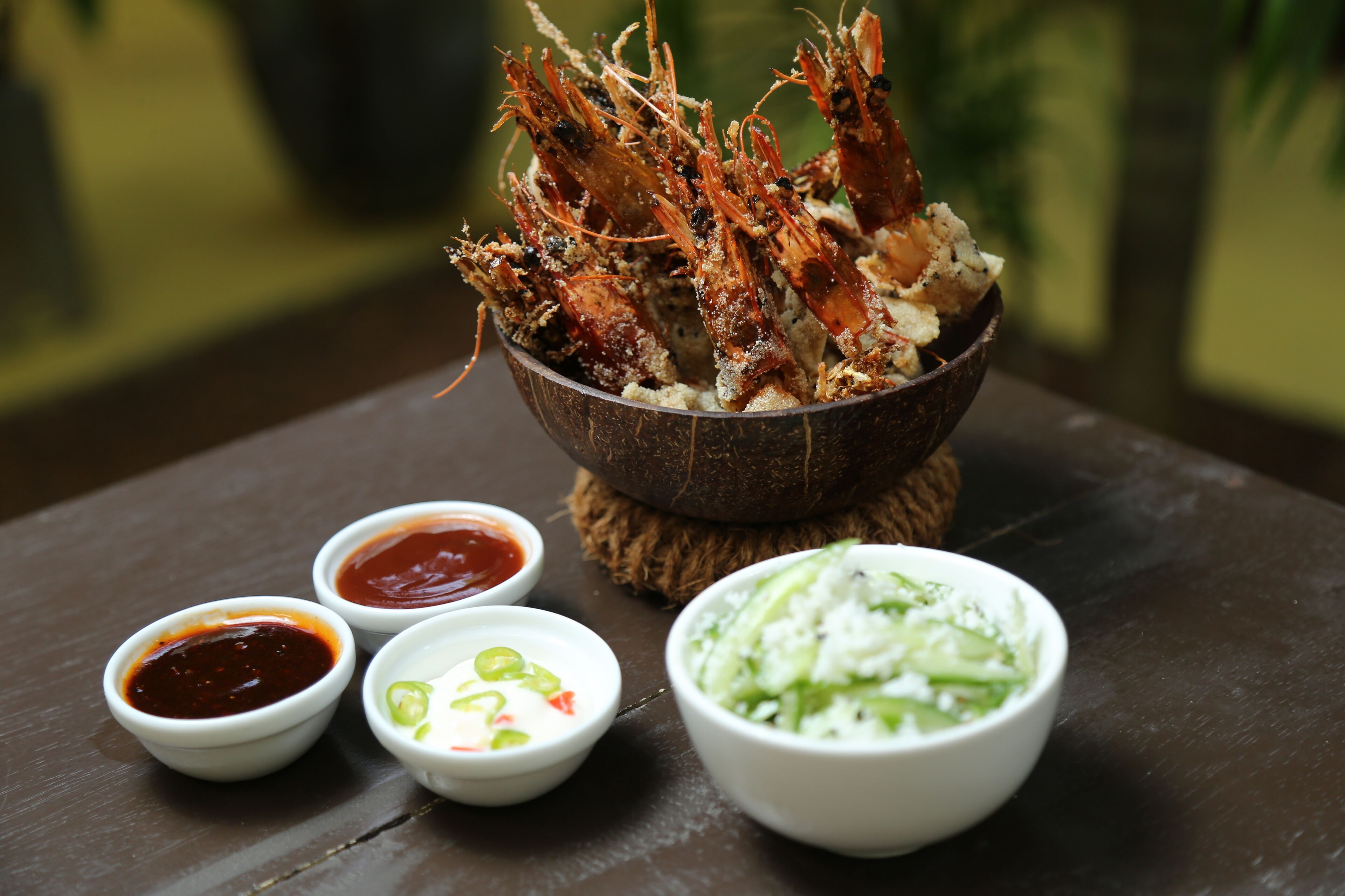 A bowl of cooked shrimp with dipping sauces and a side salad.