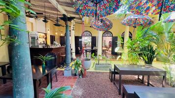 Un espacio interior con restaurante, mesas y sombrillas florales colgantes.