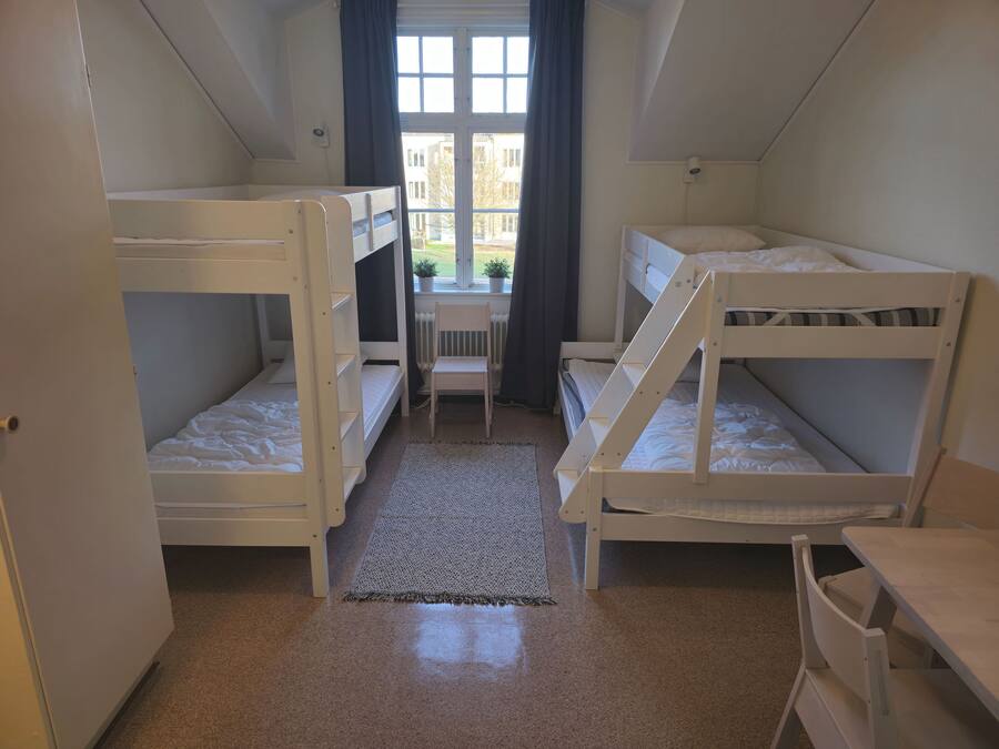 Un dormitorio con literas, un escritorio y una silla.
