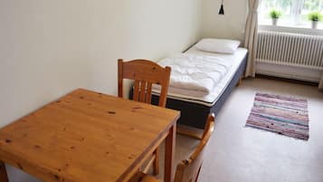 A small bedroom with a single bed, a wooden table, and a radiator.