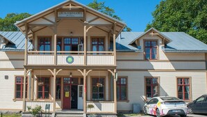 A two-story building with a balcony, a sign above the entrance, and a car parked in front. - Ronneby Brunnspark Vandrarhem och B&B - Hostel (Ronneby)