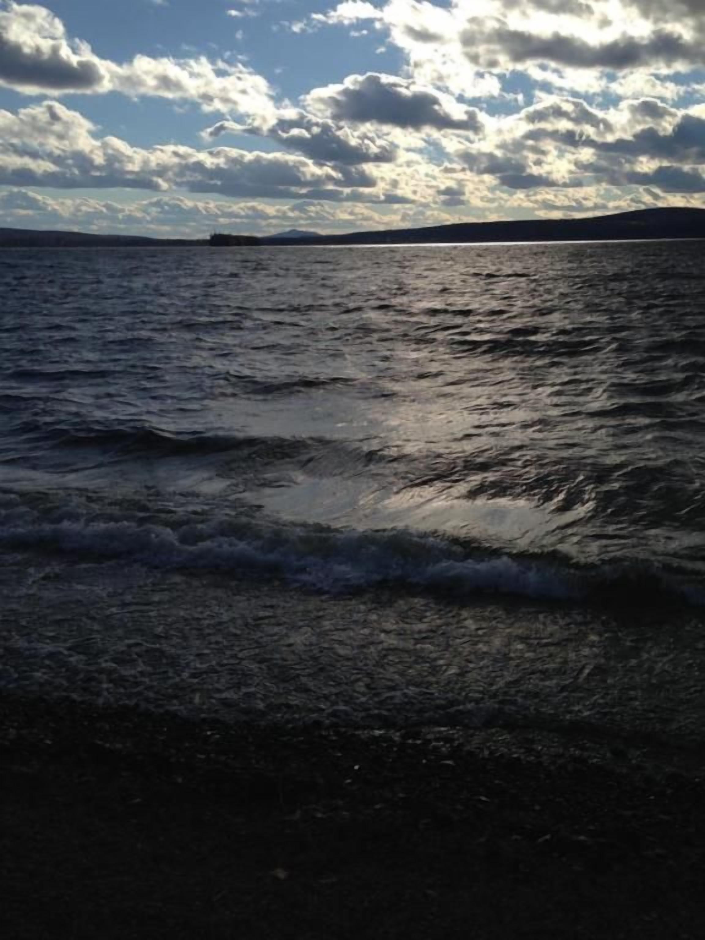 A beach with waves and a cloudy sky.